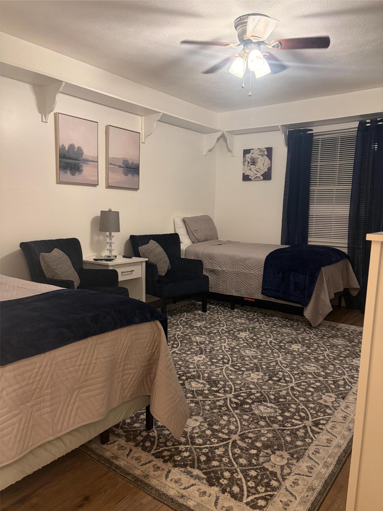 Bedroom with two beds, armchairs, and ceiling fan